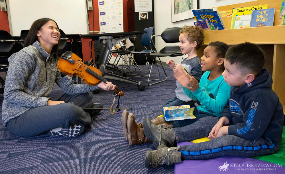 Jasmyn Mitchell demonstrated her violin skills to Maxwell Brenner, Khalie Collins and Daniel Powers, all 4, at University City Children’s Center in December. Mitchell was a student at the center nine years ago and now volunteers to work with children there. She is a freshman at Rosati-Kain High School.