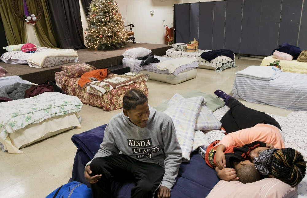 Jeremy Anderson, left, Chasidy Ellis and their one-year-old son, Chance Anderson, prepared to sleep Dec. 21 at Christ the King Church in University
City. The church serves as a night site for Room at the Inn, a ministry that provides temporary emergency shelter for homeless women and families.
Room at the Inn uses space in churches, synagogues and mosques to house people.