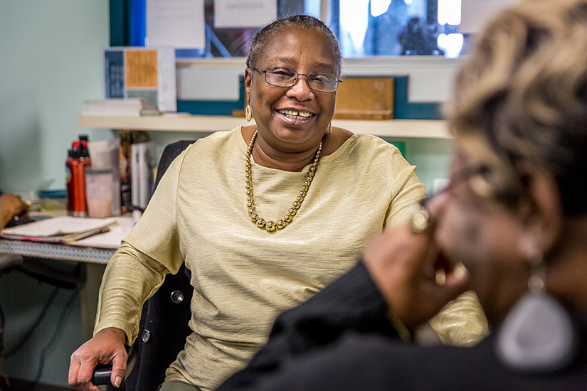 Delnita McGhaw, left, talked with housing navigator Delores Bowman Jan. 30 at her desk at St. Patrick Center. McGhaw, who was formerly homeless, works as an intake receptionist at St. Patrick Center.