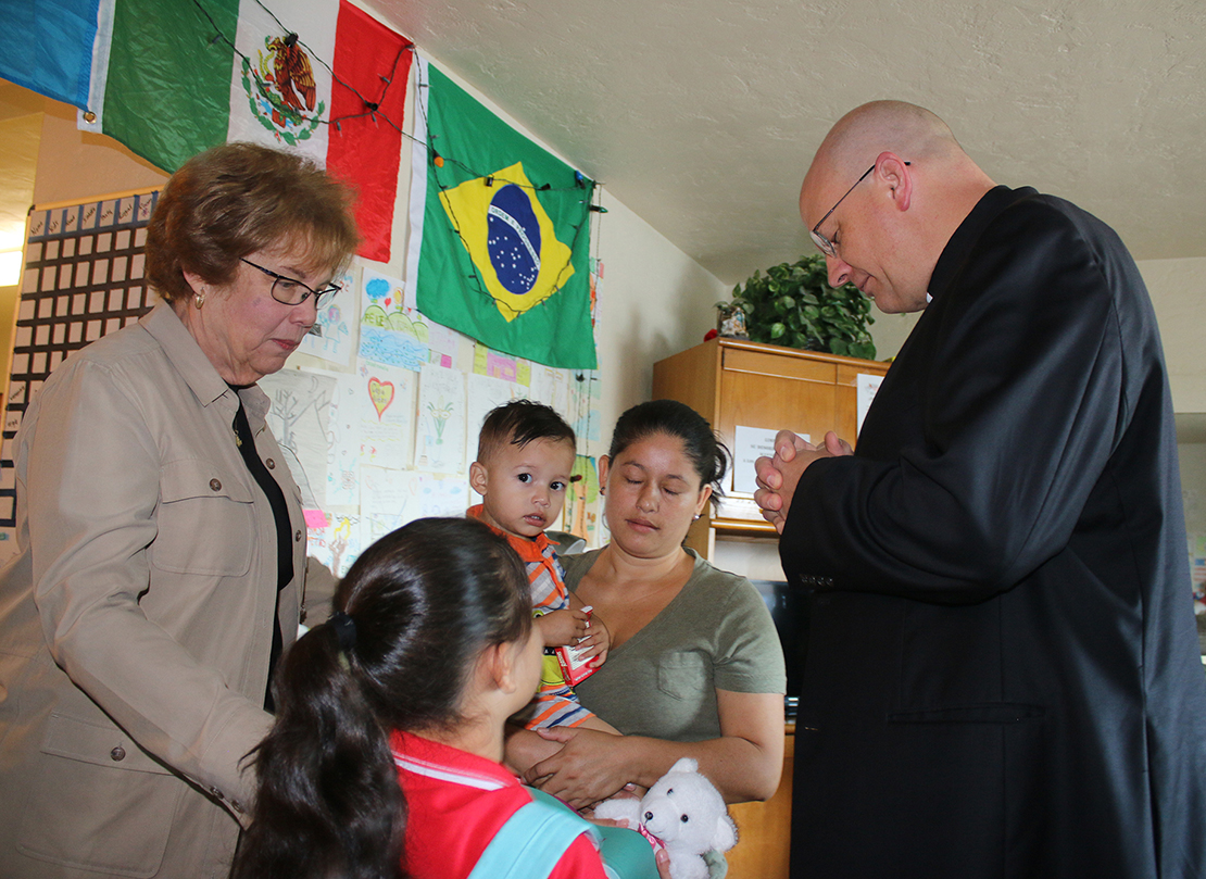 Dominican Sister Donna Markham, president and CEO of Catholic Charities USA, and Bishop Edward J. Weisenburger of Tucson, Ariz., prayed July 12 with a young family moments before they leave Casa Alitas, a family shelter in Tucson, for a bus trip that will take them to family in Baltimore.