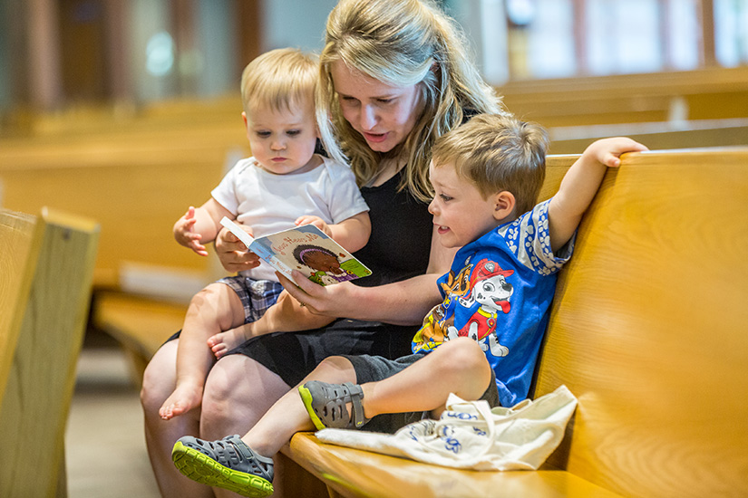 Melissa Bommarito read a book to her sons, 18-month-old Lucas and 3-year-old Henry, before Mass at St. Catherine
Laboure Parish.