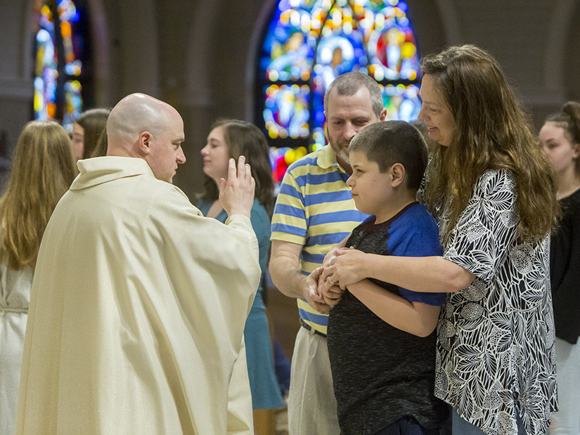 Father James Theby blessed Eli Homyk at the All Abilities Mass at Our Lady of Lourdes Church in Washington. Eli attended the Mass with his parents, Chris, center, and Stacey, right, and his sister Elizabeth.