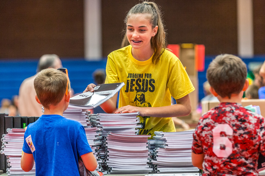Shea Block, a member of the St. Vincent de Paul youth group at Our Lady Queen of Peace Parish in House Springs, smiled as she distributed notebooks for students of low-income families.