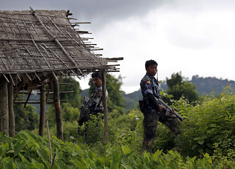 Police stand guard in 2017 after finding 10 bodies buried in a mass grave in the village of Maungdaw, Myanmar. A U.N. fact-finding mission said senior military officials in Myanmar must be prosecuted for genocide and war crimes against Rohingya Muslims and other ethnic minorities. 