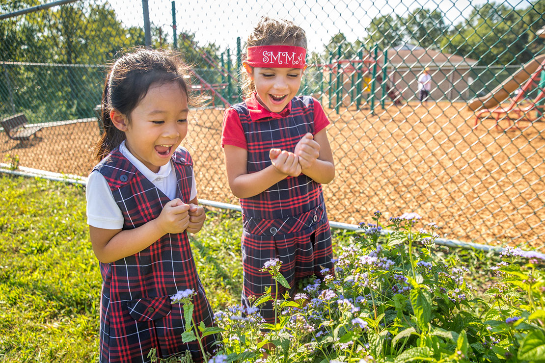Kindergarten students Jacquelin Vu and Juliana Talleur reacted to seeing moths flying through flowering mint in a butterfly garden at St. Margaret Mary Alacoque School Sept. 18.