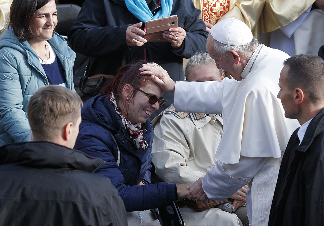 Pope Francis greets a woman as he meets the disabled before celebrating Mass in Freedom Square in Tallinn, Estonia, Sept. 25.