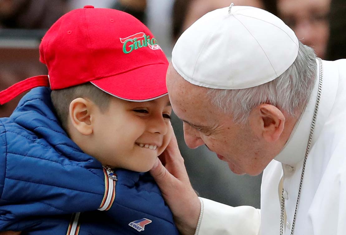 Pope Francis greeted a child as he arrived to lead his general audience Oct. 31 in St. Peter’s Square at the Vatican.