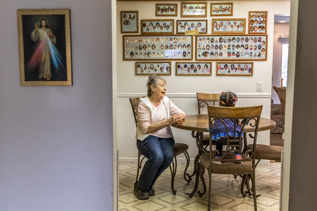 Marie Peters talked with her foster child, Noel, in the kitchen on Nov. 12. Marie and her husband Ron have been adopting and fostering children since the 1960s. The pictures along the back wall of their kitchen feature many of the almost 200 children they have fostered.
