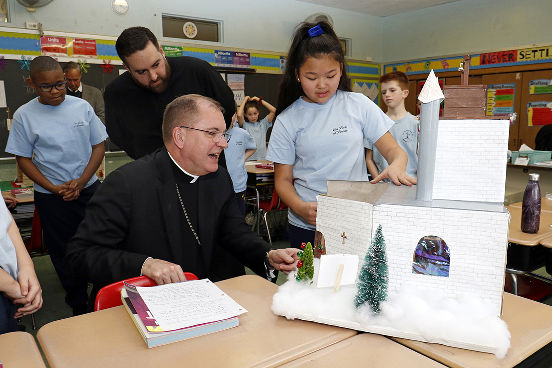 Bishop John O. Barres of Rockville Centre, N.Y., looked at a model of a church building designed and constructed by fifth-grader Emma McDermott at Our Lady of Lourdes School in Malverne, N.Y., Jan. 28. Bishop Barres is visiting schools throughout his diocese as they celebrate Catholic Schools Week, observed Jan. 27 through Feb. 2 this year.