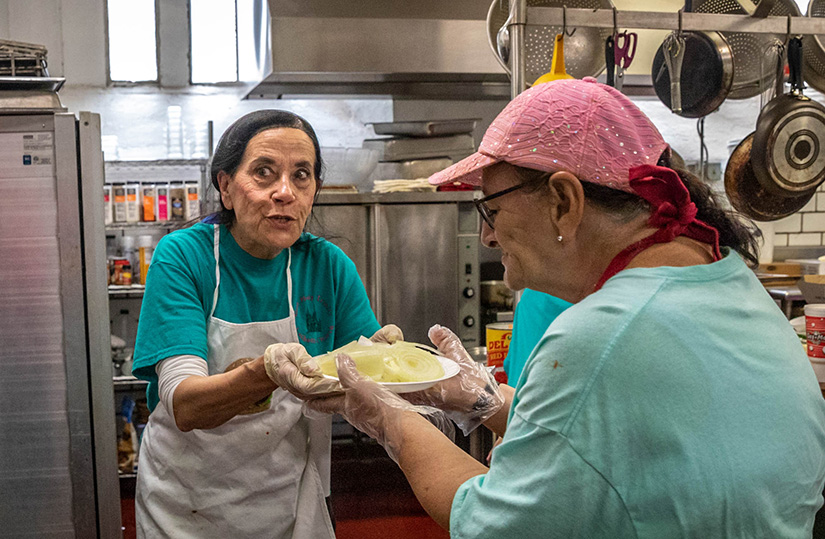Nicky Hoxworth, left, handed a plate of onions to fellow volunteer Schareen Fichtenmeyer at the Most Holy Trinity Parish fish fry. Hoxworth and Vickie Deason spearheaded the return of fish fries at the church after about a 20-year hiatus.