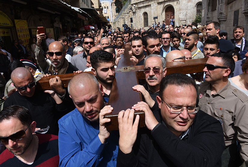 Mousa Kamar, front right, and his son, Youssef, far left corner, carried the large wooden cross during the Good Friday procession on the Via Dolorosa in Jerusalem’s Old City March 25, 2016. Mousa Kamar and his sons are carrying on the tradition of his grandfather and father in carrying the cross on Good Friday.