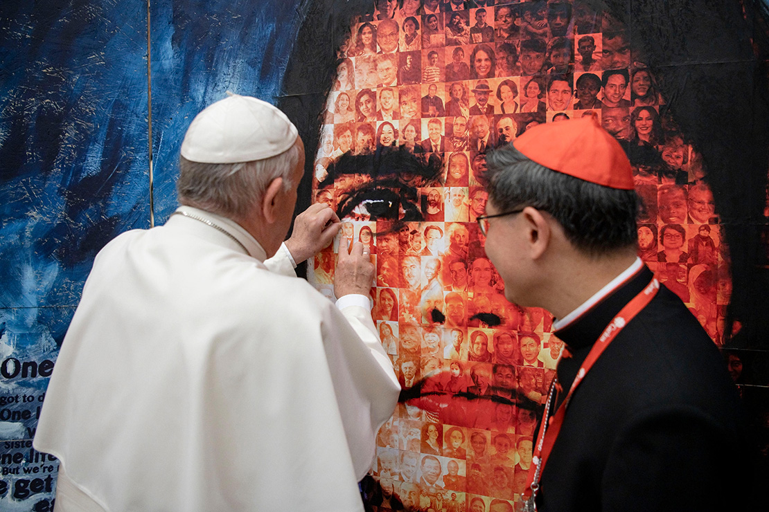 Pope Francis placed a picture of his parents onto the “Share the Journey” photo mosaic during an audience with delegates attending the general assembly of Caritas Internationalis at the Vatican May 27. At right is Philippine Cardinal Luis Antonio Tagle of Manila, president of Caritas Internationalis. The mosaic of migrants, world leaders and Caritas workers illustrates how humanity forms one family and is sharing one journey. Being part of one family, Cardinal Tagle said, also means sharing responsibility for the family home, which is the earth. Efforts to protect human beings and protect the environment at the same time are part of what the Catholic Church calls “integral ecology.”