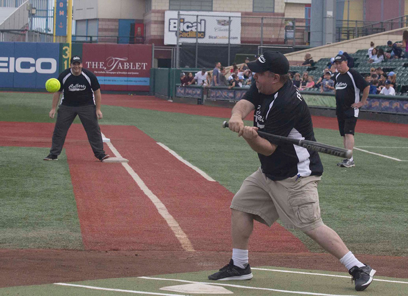 Father James Kuroly swung at a pitch while Father Chris Bethge led off first base during Collars vs. Scholars games at MCU Park on Coney Island in Brooklyn June 17. For the second straight year, the Brooklyn clergy showed their prowess on the softball diamond with a 2-1 win over principals and teachers of diocesan schools.