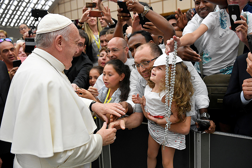 Pope Francis smiled at a young girl after he exchanged his zucchetto with one brought by her family at the pope’s general audience in Paul VI hall at the Vatican Aug. 7. Returning for the first audience following the summer break, the pope continued his series of talks on the Acts of Apostles and reflected on the words spoken by Peter and John before healing a disabled man asking for alms at the entrance to the temple.