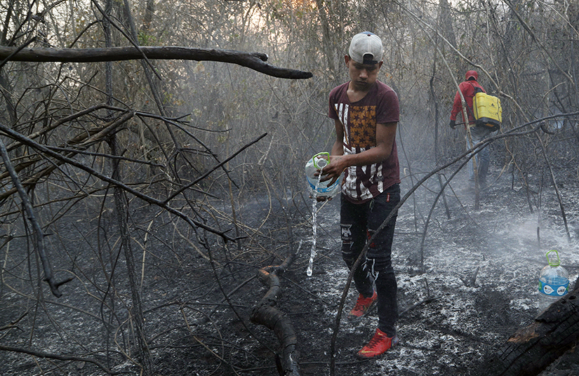 Volunteers extinguished a fire in Aguas Calientes near Robore, Bolivia, on Aug. 24. Farmers commonly set fires in this season to clear land for crops or livestock, but temperatures and winds can quickly whip flames out of control, and most communities lack firefighting equipment.