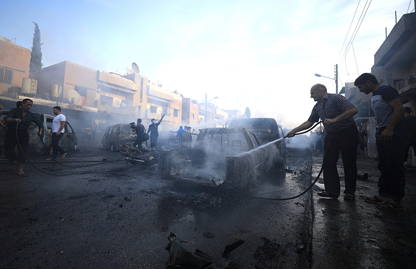 A man sprayed water at the site of a car bomb blast in Qamishli, Syria, Oct. 11. The ongoing Turkish military operation in northeastern Syria is having a devastating humanitarian impact on civilians, according to humanitarian groups.