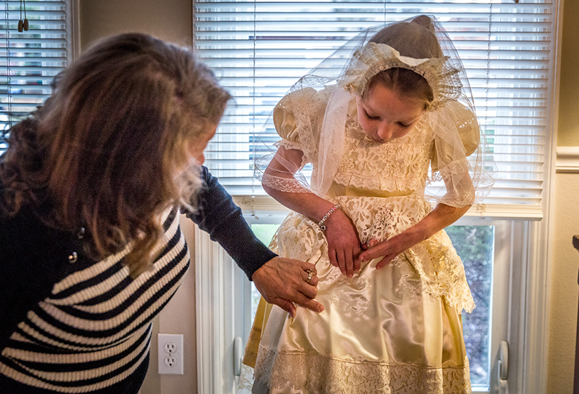 Paula Hrin adjusted the First Communion dress on her granddaughter, Vanessa Hrin, pointing out where her name was embroidered. In 1959, Paula’s mother, Dolores Perniciaro, made a First Communion dress for Paula; this April, Vanessa will be the 16th family member to wear the dress for her First Communion.