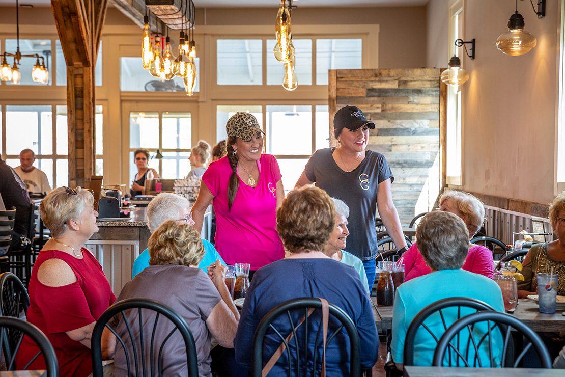 Sisters Cami Flynn, left, and Cori Breen talk to customers who are eating lunch at The Grotto in Flint Hill. Flynn and Breen operate The Grotto Grill and make sure that the restaurant reflects their faith lives.