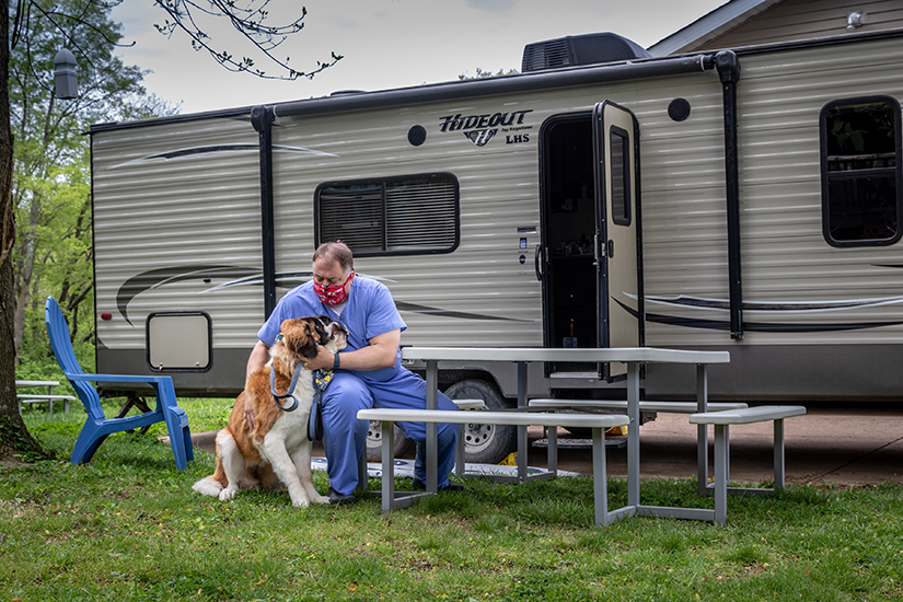 Dr. Brian Gosser petted his 8-month-old St. Bernard, Clare, outside the camper he quarantined himself in after he started feeling sick. Gosser, an OB/GYN, has quarantined in the camper outside his home in Sunset Hills even though he tested negative for COVID-19.