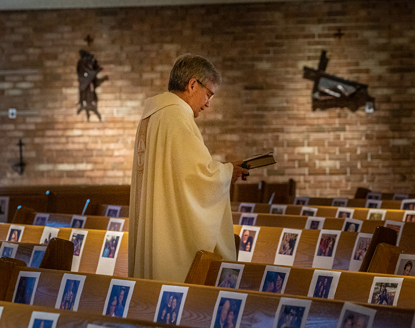 Father Bill Kempf processed out past photos of parishioners on the pews after celebrating Mass at St. Justin Martyr in Sunset Hills May 2. Parishioners at St. Justin attached the photos to the pews to surprise Father Kempf, the pastor, to let him know they were with him in spirit.