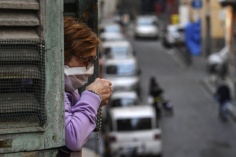 A woman prayed in a window opening overlooking a street in Milan, Italy, March 21 during a nationwide lockdown to reduce the spread of COVID-19. A recent study showed an increase in prayer and religious fervor in Italy amid the coronavirus pandemic.
