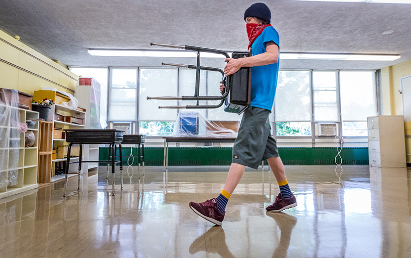 Billy Dugan arranged desks to conform to social distancing requirements at St. Mary Magdalen School in Brentwood on July 21. Catholic schools in the archdiocese are releasing plans for returning to in-person learning, with social distancing an important aspect of many plans.