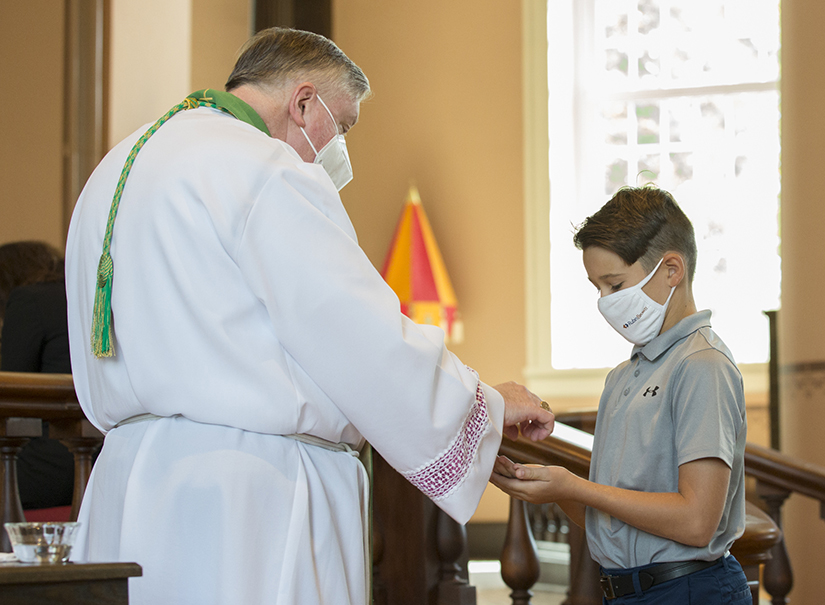 Nicholas Sackman, 10, received Holy Communion after Mass on Aug. 30 from Archbishop Mitchell Rozanski at the Basilica of Saint Louis, King of France (Old Cathedral).