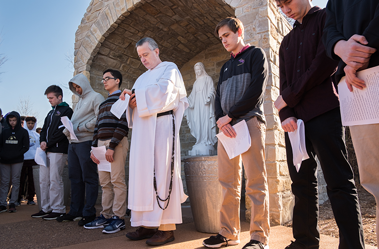 Father DePorres Durham, OP, timed 100 seconds of silence for victims of gun violence while praying with students March 14 at Christian Brothers College High School in Town and Country. Students gathered around the Marian grotto at the school to pray as part of the national movement of school walkouts to call for gun policy reform and the end of violence.