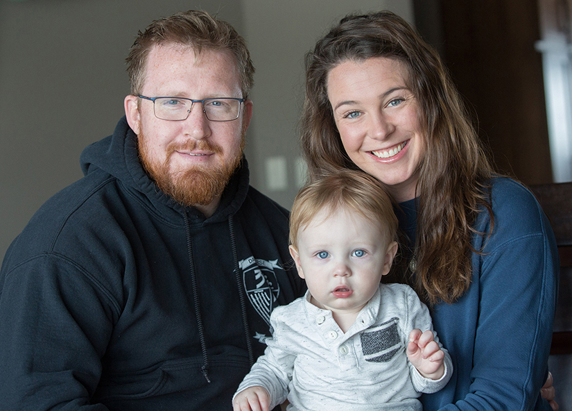 Colin and Julia Faust posed for a photo with their son, Leo, in their home Oct. 26. Colin Faust, a Marine who was injured in an explosion in Afghanistan, views a Miraculous Medal he was wearing as a sign that God saved his life.