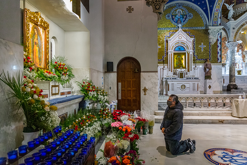 Luis Ortiz knelt in front of a shrine full of flowers as parishioners celebrated the feast of Our Lady of Guadalupe at St. Cecilia Church in St. Louis Dec. 12. The celebration included songs, prayers, Mass and traditional Mexican treats.