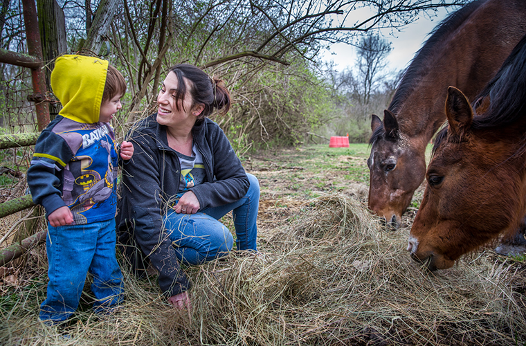 Sally DeIuliis and her son, Emmerson, fed their neighbor’s horses in Black Jack on April 15. DeIuliis was six months pregnant with Emmerson and addicted to heroin when she received help from Catholic Charities’ Queen of Peace Center and the WISH Clinic at SSM St. Mary’s Hospital.