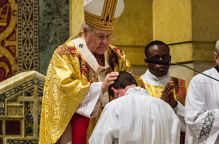 Archbishop Robert J. Carlson laid hands on Deacon Christopher Rubie at his ordination to the transitional diaconate last year. 