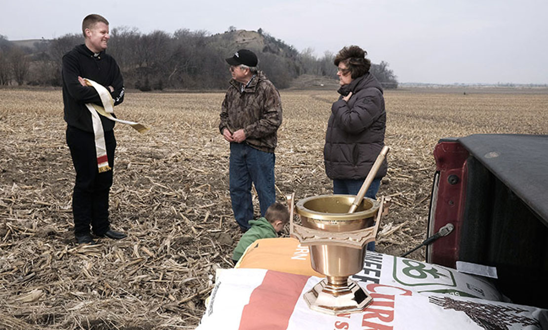 Father Andrew Sohm talked with farmers Marlan and Sherry Rolfes of Newcastle, Neb., after blessing their fields April 11.