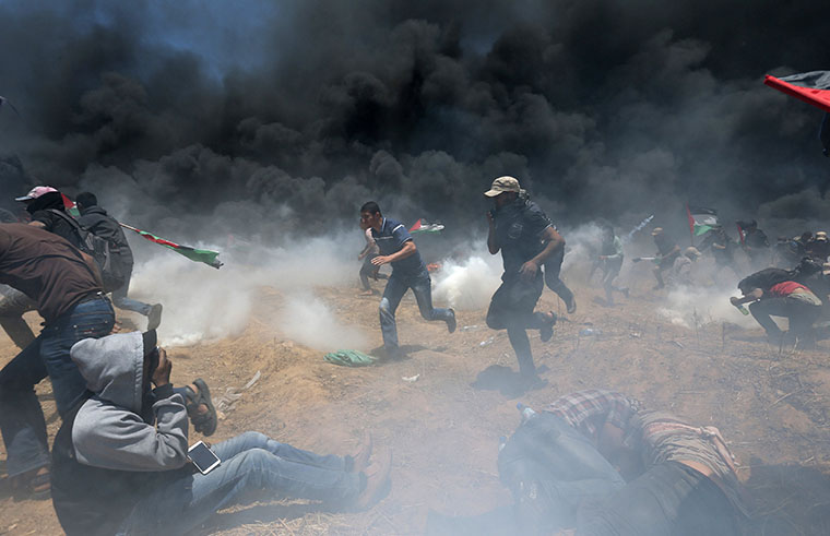 Palestinians ran for cover from Israeli fire and tear gas at the Israel-Gaza border during a protest against the U.S. embassy move to Jerusalem May 14. 
