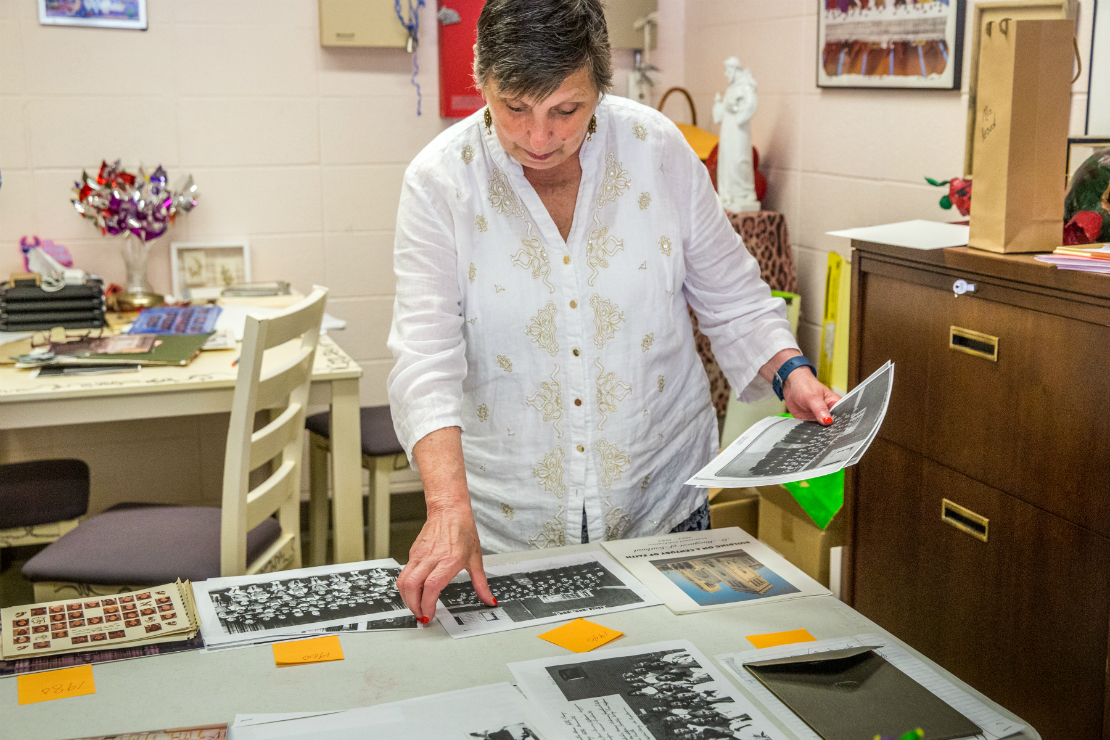 Juliann DePalma Hesed, principal of St. Margaret of Scotland Parish School, organized years of photographs and paraphernalia to be placed inside a time capsule celebrating 100 years of the school.