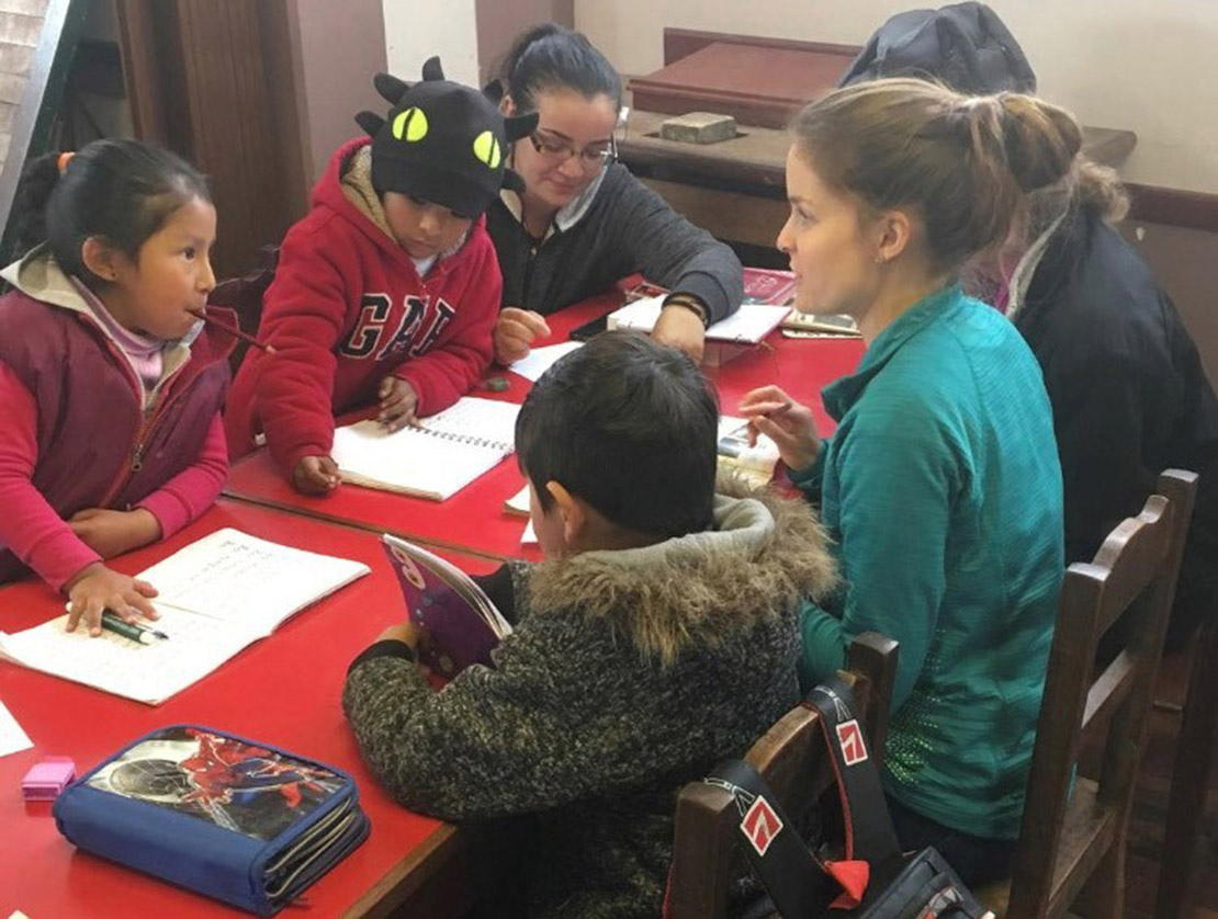Young adults from St. Louis on a trip to the archdiocese’s Latin America Apostolate, including Mary Staten, right, and Jessica Burns, helped students with homework while visiting a tutoring program of Maria Reina Parish in La Paz, Bolivia. The apostolate supports the parish, staffed by Archdiocese of St. Louis priests.