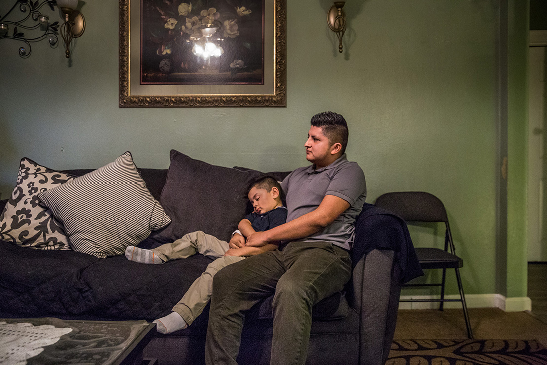Eric Reyes held his sleeping 4-year-old son, Eric Jr., while watching television March 6 at the family’s home. Reyes, who has been covered under the Deferred Action for Childhood Arrivals program since he was 17, says that despite the roller coaster of DACA in the political world, he has felt very supported by his parish and those that get to know him.