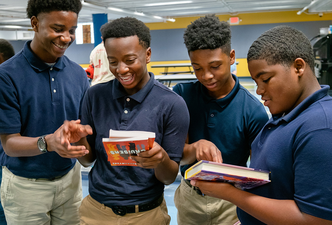 Loyola Academy students from left, Elijah Thomas, Quincy Gibson, AJ Walker and Reggie Griffin reviewed books offered to students by The Little Bit Foundation at the school in St. Louis Sept. 18. Staff at the foundation say the goal is to remove barriers to education for students living in poverty through partnerships and programs that serve the needs of the whole child.