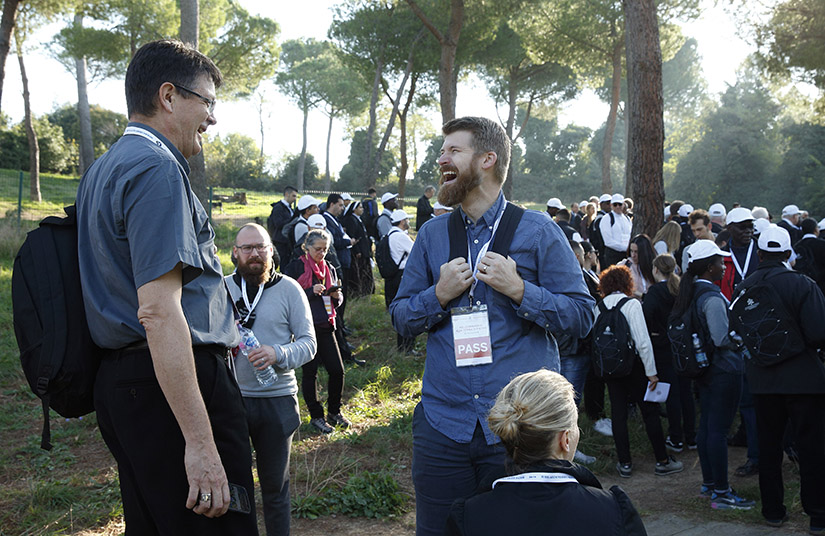 Bishop Pierre Jubinville of San Pedro, Paraguay, shared a laugh with synod observer Jonathan Lewis from the Archdiocese of Washington during a stop in a pilgrimage hike from the Monte Mario nature reserve in Rome to St. Peter's Basilica at the Vatican Oct. 25. Participants in the Synod of Bishops on young people, the faith and vocational discernment, and young people from Rome parishes took part in the hike.