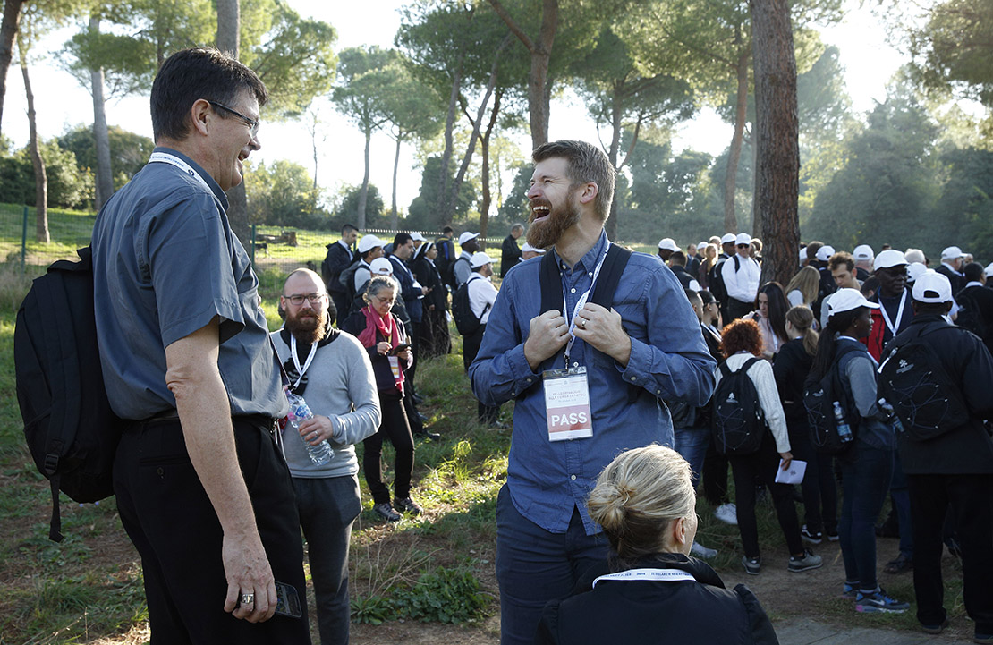 Bishop Pierre Jubinville of San Pedro, Paraguay, shared a laugh with synod observer Jonathan Lewis from the Archdiocese of Washington during a stop in a pilgrimage hike from the Monte Mario nature reserve in Rome to St. Peter’s Basilica at the Vatican Oct. 25. Participants in the Synod of Bishops and young people from Rome parishes took part in the hike.