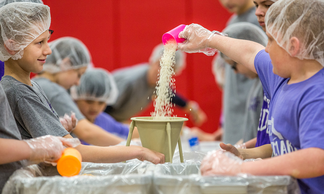 Nick Litvinov held a funnel as Beck Ragain poured rice into it as the boys prepared meals for poor people in Haiti. The project was part of St. Mark School’s “Do It for Brett” service day on Jan. 11.