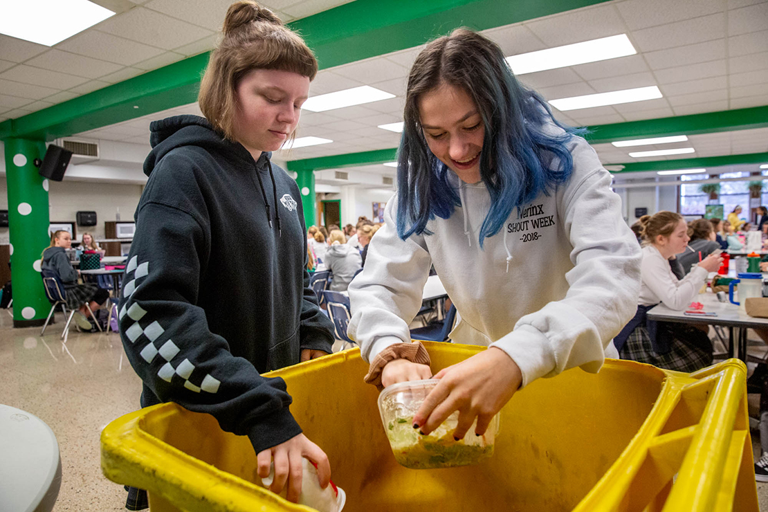 Amanda Glore and Emily Carril emptied containers into a composting bin at Nerinx Hall High School. The school’s partnership with St. Louis Composting will help slow the stream of organic waste buried at landfills.
