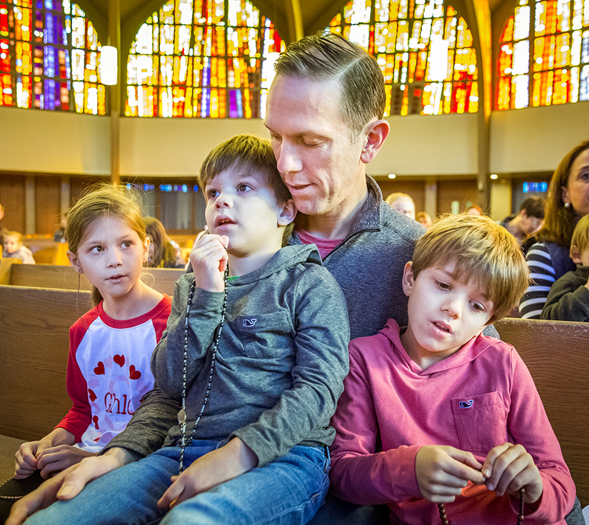 Matt Eversgerd and his children Cloe, Davis and Jack prayed the Rosary with other parishioners after Saturday morning Mass at St. Clement of Rome Parish.
