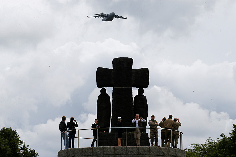 A plane flew over a cross at La Cambe German war cemetery in Normandy, France, June 5, 2019, during a remembrance ceremony held as part of commemorations of the 75th anniversary of D-Day. Archbishop Timothy P. Broglio of the U.S. Archdiocese for the Military Services said, "We ask God that their sacrifice not be in vain. We beg Him to transform our power to turn war into a force for peace, to transform our weapons into plowshares, to give us the ability to negotiate, to talk and to listen."