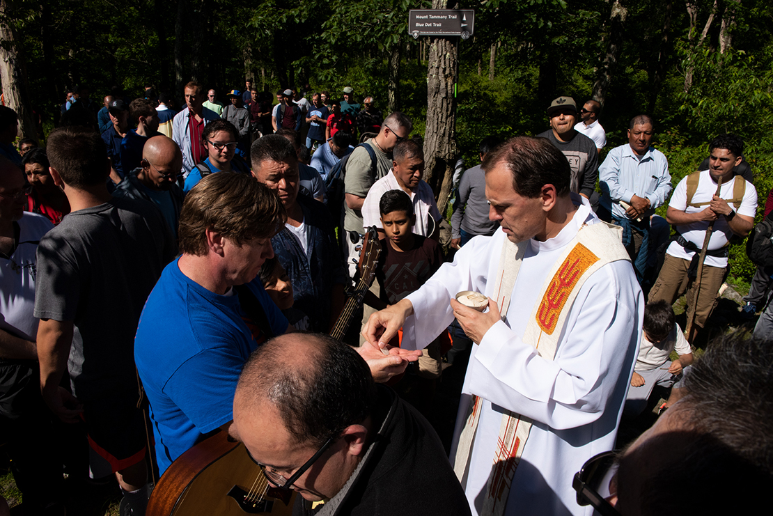 Divine Word Father Krzysztof Pipa, parish administrator of St. Ann Parish in Browns Mills, N.J., distributed Communion at the ‘Mass on Top of the Mountain’ on Mount Tammany in New Jersey.