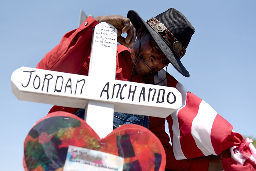Curtis Reliford knelt Aug. 5 next to a cross in honor of Jordan Anchando, one of the victims of a mass shooting Aug. 3 at a Walmart store in El Paso, Texas.