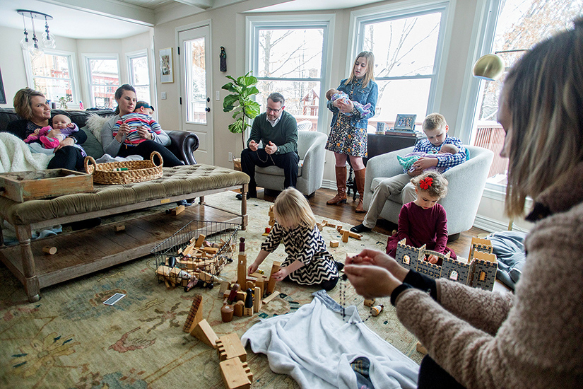 Jennie and Kevin Punswick, pictured at far left and in front of window, prayed the Rosary with family and friends at their home in Overland Park, Kan., Jan. 12. Erin and Tom Joerger, Erin on couch, and Samantha O'Malley in foreground at right, were among those who joined them. Baby-holding duty was shared by all, including 10-year-old John Punswick.