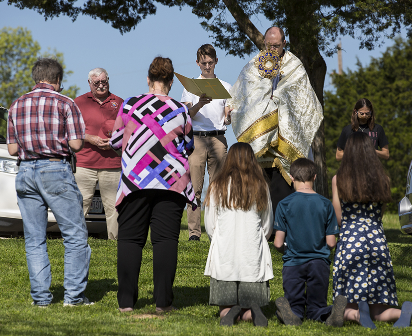 Father Raymond Buehler, parochial administrator of Good Shepherd Parish in Hillsboro, administered a eucharistic blessing May 2, bringing the Blessed Sacrament to dozens of homes in the parish. Praying in front of their home were the Eimer family, from left, Steve and Karen Eimer and their kids, Rachel, Samuel and Rita.