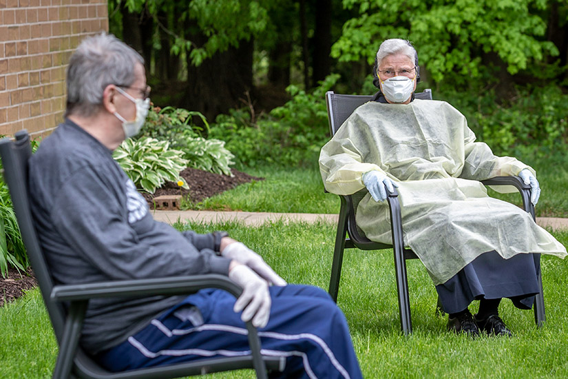 Sister Marie Paul Lockerd, RSM, chatted with Father Phil Krahmann outside of Regina Cleri in May. Sister Marie Paul, a physician, was treating Father Krahmann and other priests at the retirement residence who had been diagnosed with COVID-19.