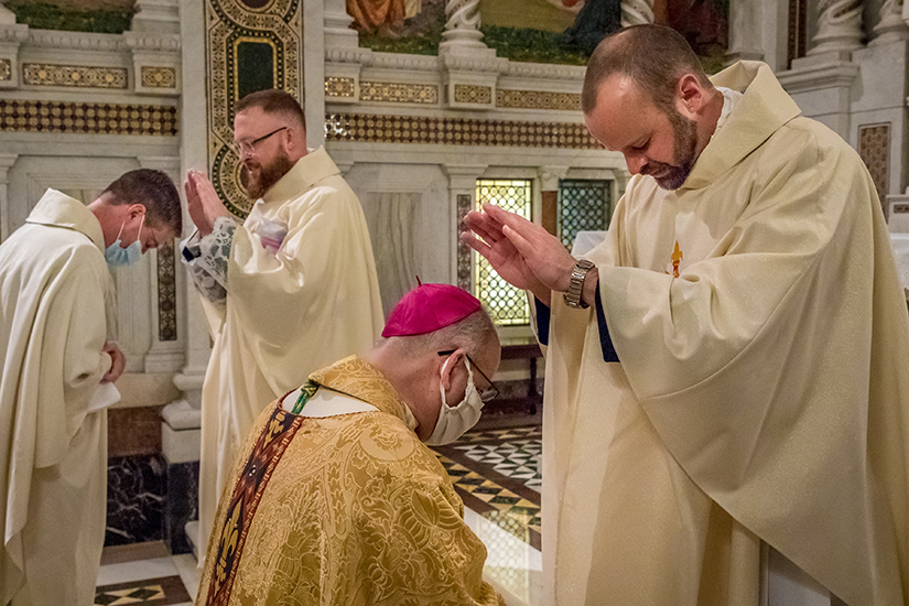 Father Christopher Smith, left, blessed Father Christopher Martin as Father Dane Westhoff, right, blessed Auxiliary Bishop Mark S. Rivituso. Fathers Smith and Westhoff were ordained to the priesthood May 23.